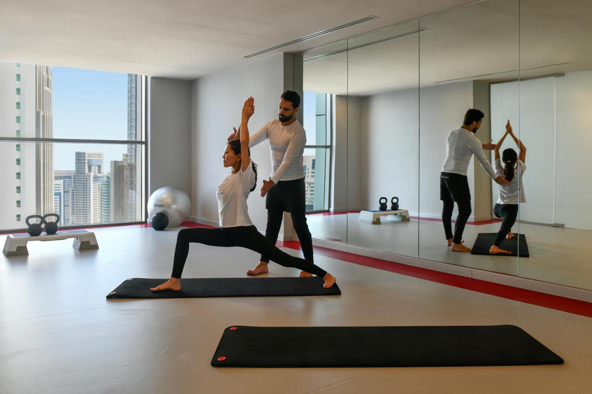 杜斯特多哈酒店 外观 照片 A personal trainer assisting a woman with a yoga workout